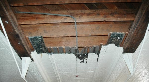 Exposed ceiling with damaged texture and visible rafters, illustrating the need for ceiling repair and renovation in home improvement projects.