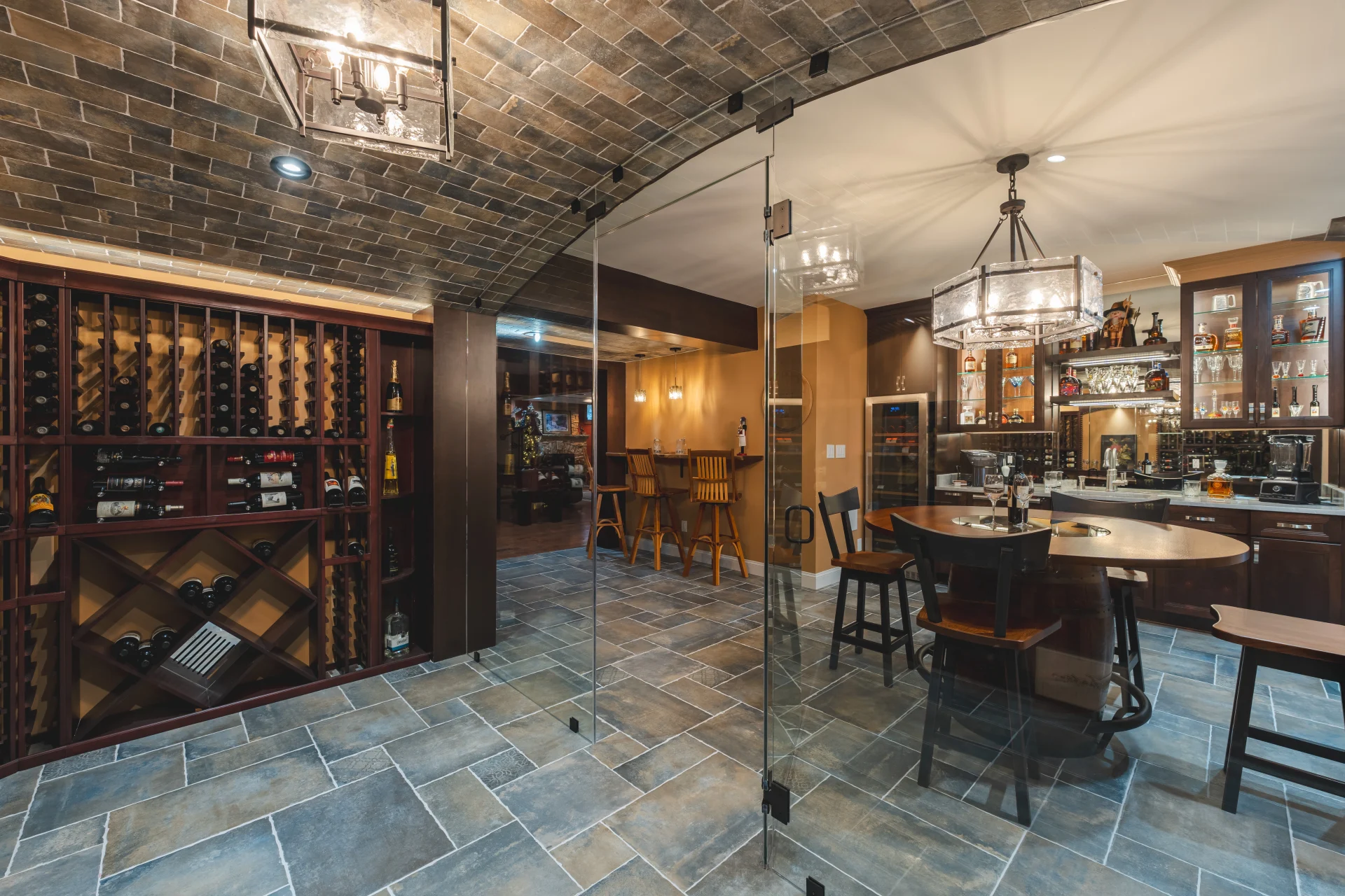 Wine tasting corner in a finished basement renovation with glass partitions, stone tile flooring, custom storage and warm lighting Wine tasting corner in a finished basement renovation with glass partitions, stone tile flooring, custom storage and warm lighting